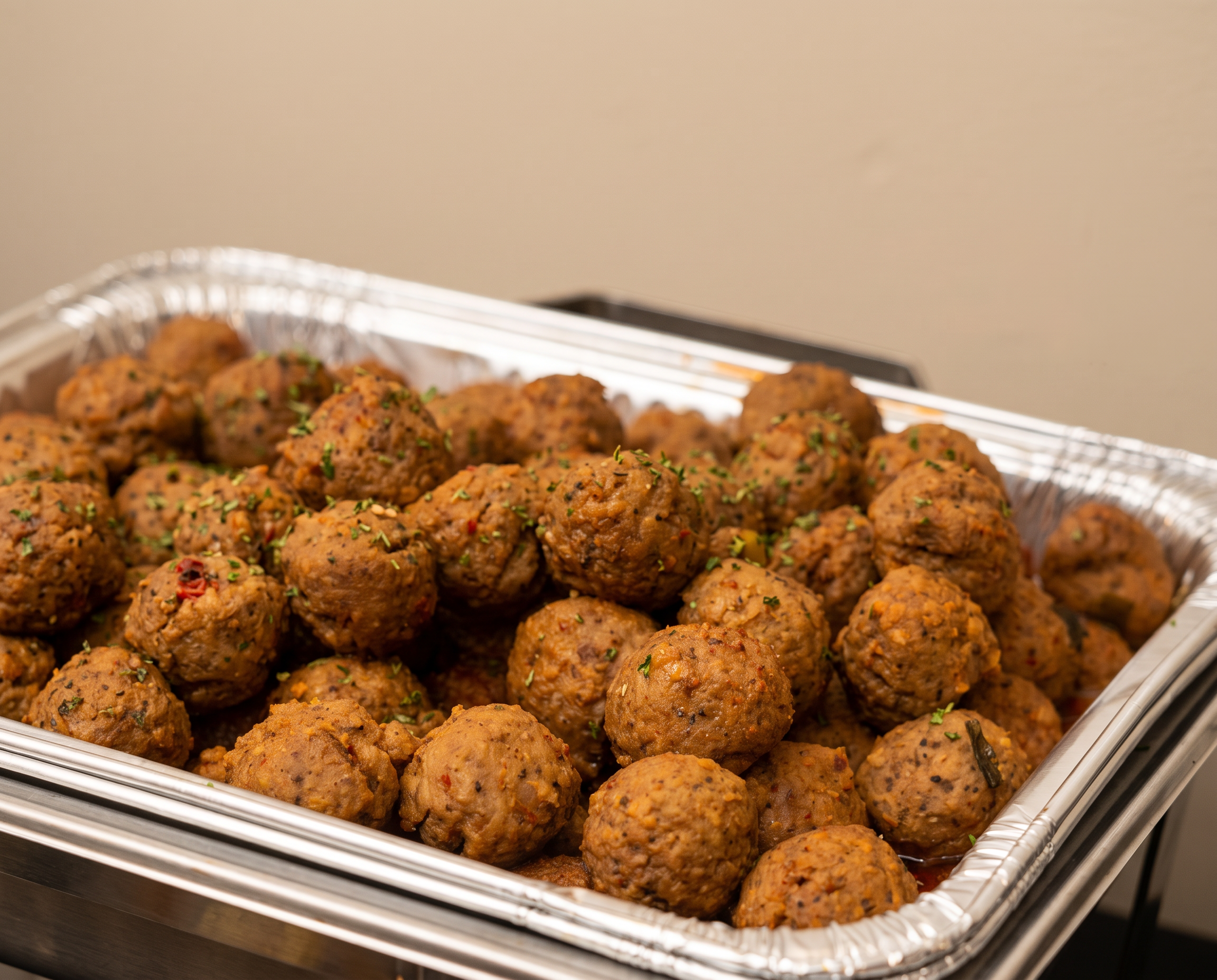 Honey chipotle meatballs garnished with parsley in a catering pan