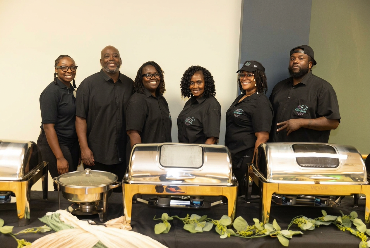 Six C&C Experience catering team members standing behind a polished buffet setup