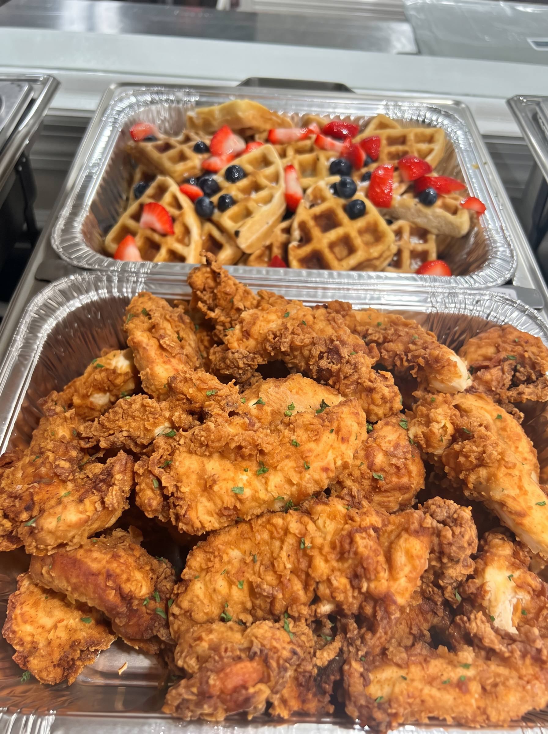 Crispy fried chicken with berry-topped waffles prepared for a catered brunch