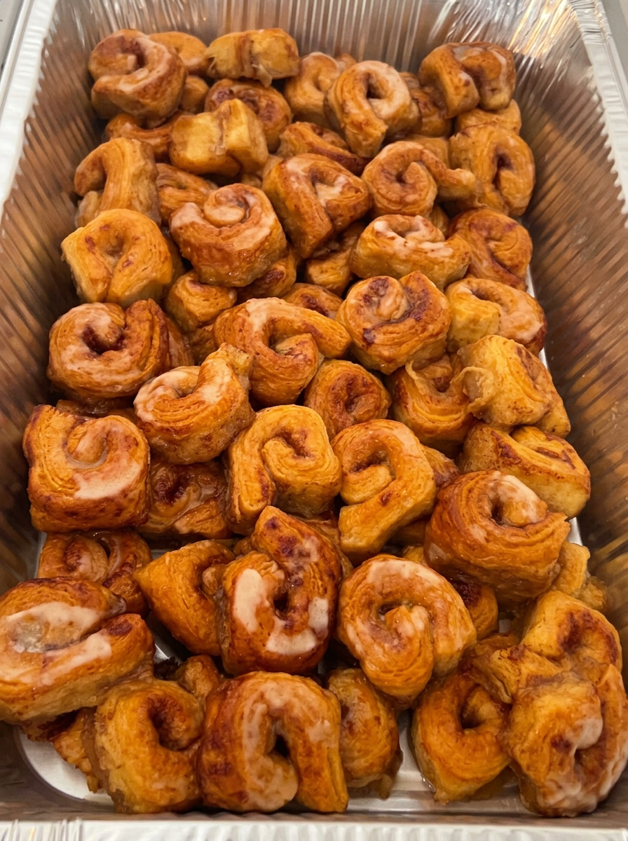 Freshly baked mini cinnamon rolls arranged in a catering tray